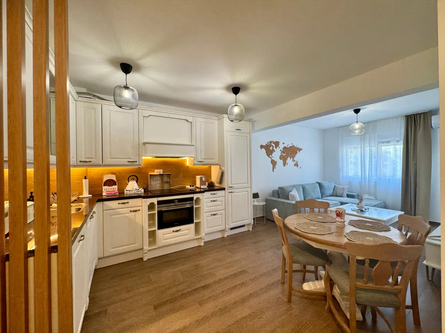 Modern white kitchen with a dining area and a view of the living room.