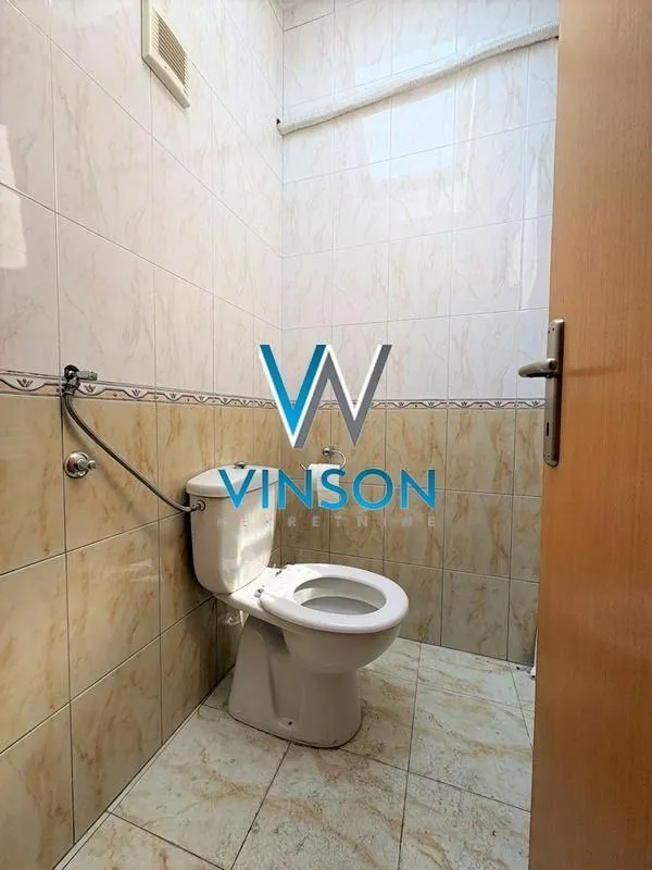 Smaller bathroom tiled with ceramic tiles featuring a toilet bowl.