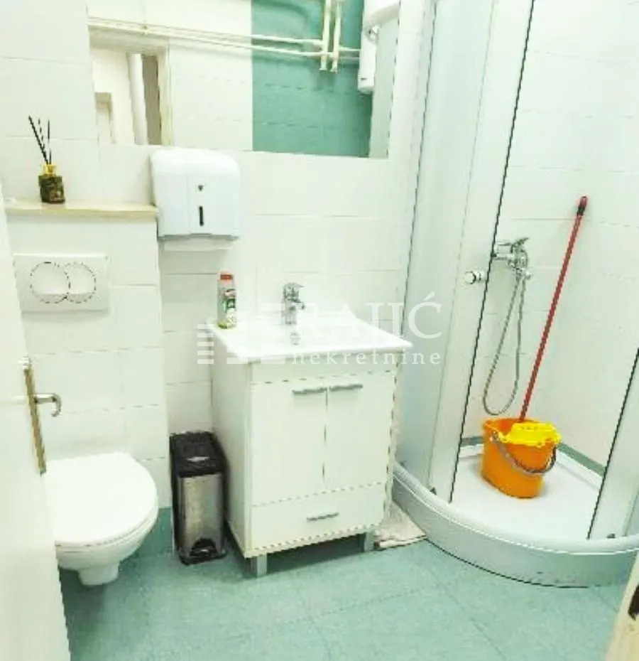 Small bathroom with a shower cabin, sink, and toilet.