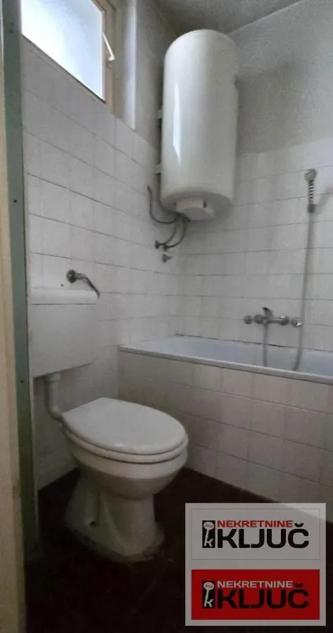 Kupatilo obloženo belim pločicama sa kadom, toaletom i bojlerom.