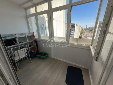 Zastakljeni balkon sa policama za odlaganje i pogledom na okolne zgrade. - image 9