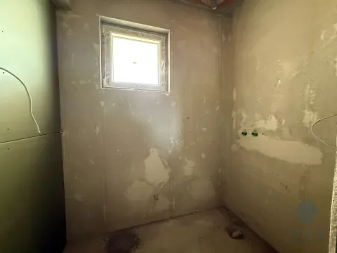 Pogled na neuređenu prostoriju u sivoj fazi izgradnje sa malim prozorom. - image 3