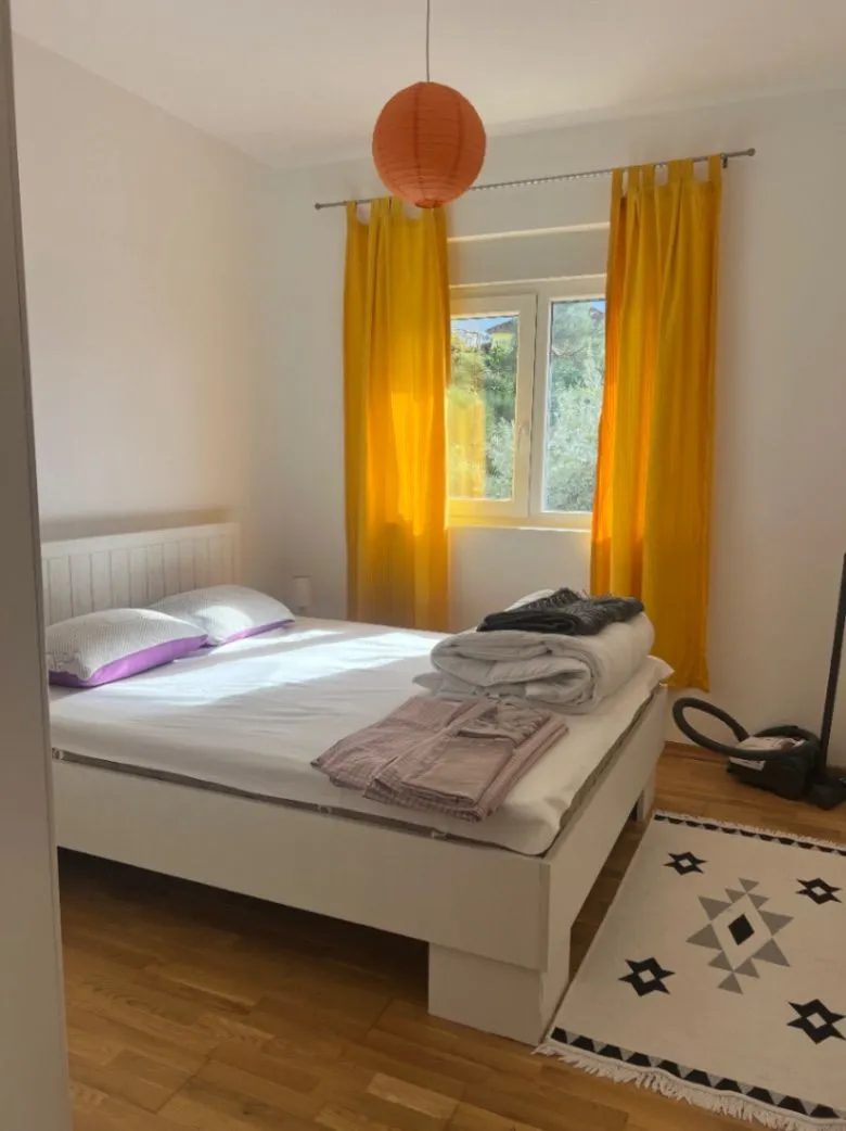 Svijetla spavaća soba sa bračnim krevetom i žutim zavjesama.