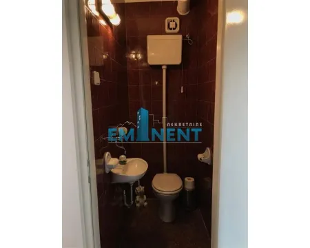 Small bathroom tiled with dark red tiles featuring a toilet and washbasin. - image 12