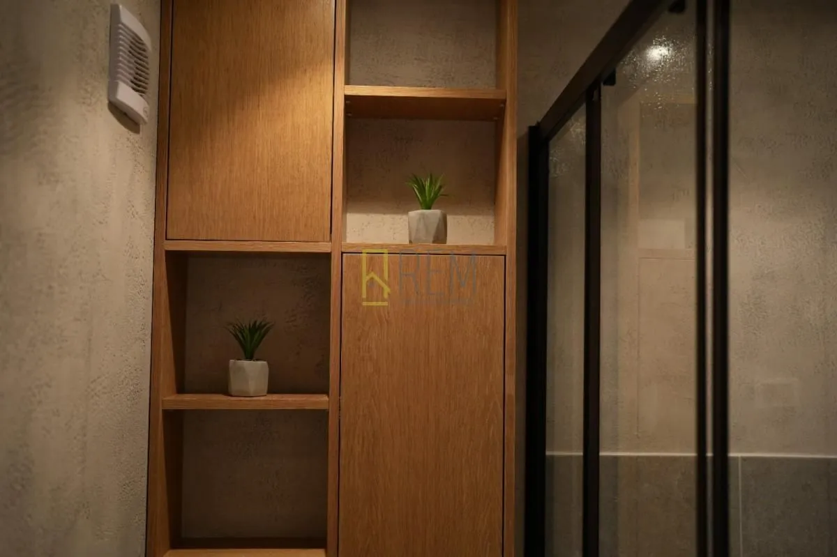 Modern wooden shelving and walk-in shower in the bathroom.