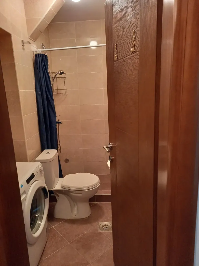 A small bathroom with a washing machine and shower.