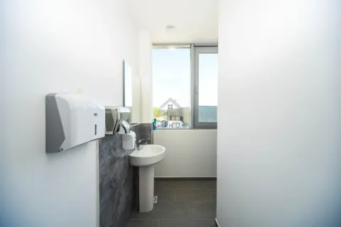 View of the sink with a mirror and soap dispensers in a modern bathroom. - image 6