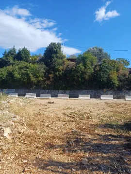 Pogled na zemljište sa rastinjem i betonskim barijerama u pozadini. - image 4