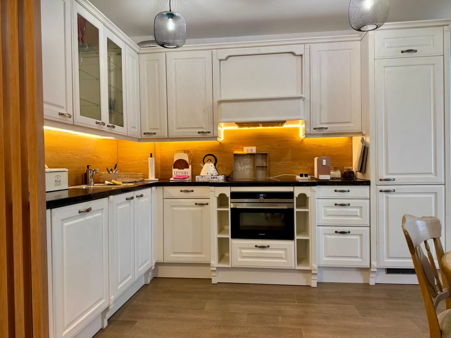 Modern white kitchen with a wooden countertop and built-in appliances.