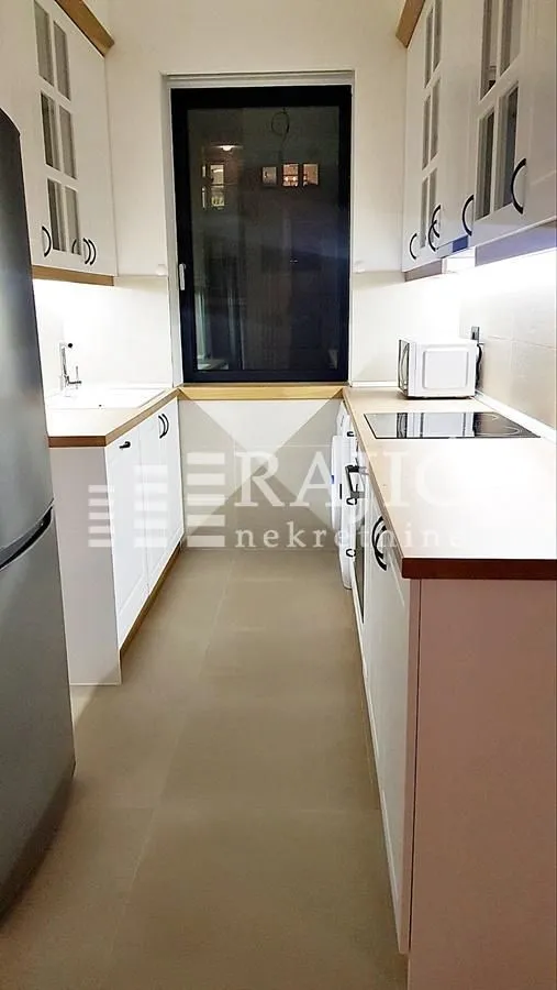 Modern white kitchen with built-in appliances and a window.