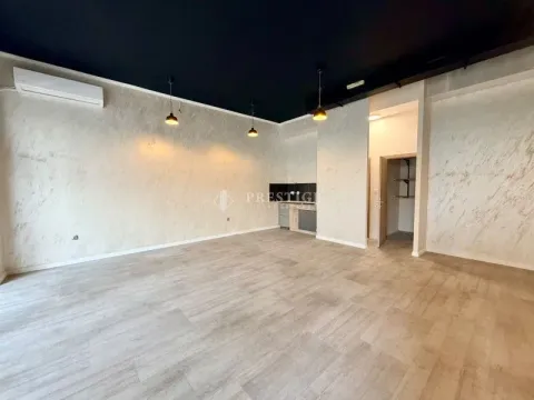 Spacious empty room with light walls and a kitchen in the background. - image 2