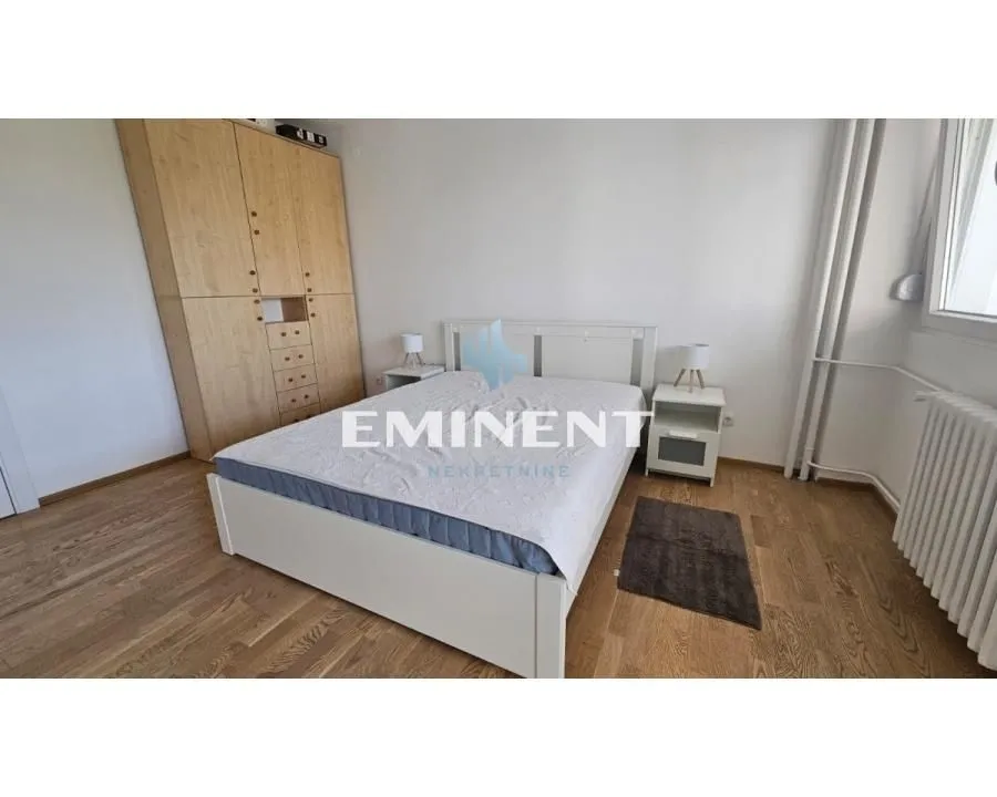 Bedroom with a double bed, wooden wardrobe and laminate flooring.