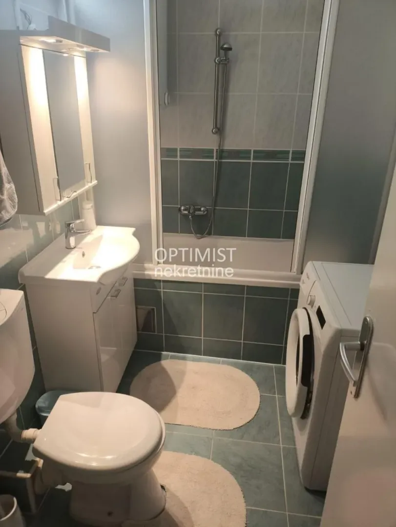 Smaller bathroom with a bathtub, washbasin, toilet, and washing machine.