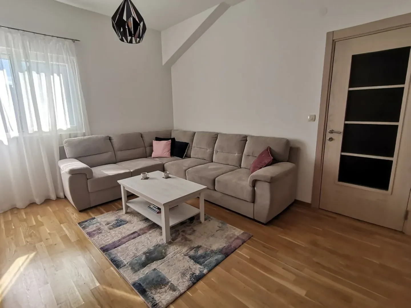 Svijetla dnevna soba sa velikom ugaonom garniturom.