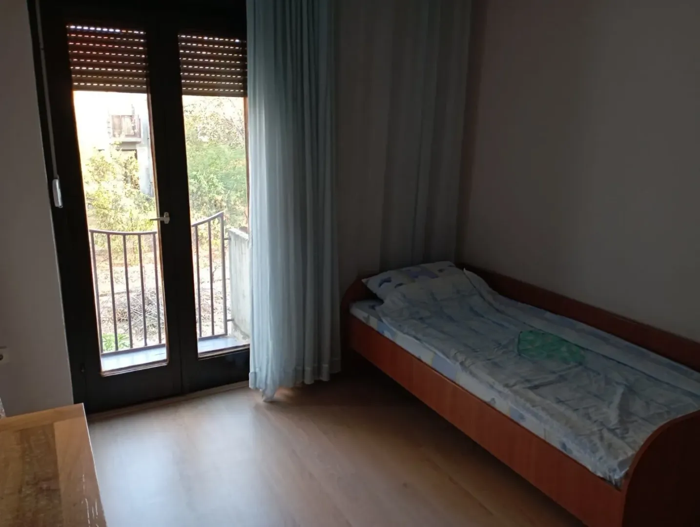 Manja spavaća soba sa krevetom i izlazom na terasu.