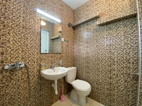 Bathroom lined with mosaic tiles featuring a washbasin, mirror, and toilet. - image 5