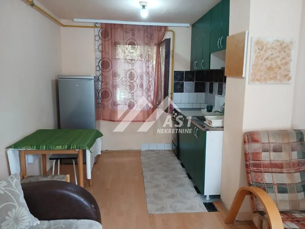 Manja kuhinja sa trpezarijskim stolom i zelenim kuhinjskim elementima.