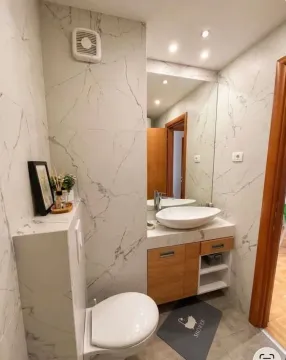 Modern bathroom with a sink, toilet, and marble-look tiles. - image 12