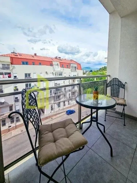 Furnished balcony with seating and a view of surrounding buildings.