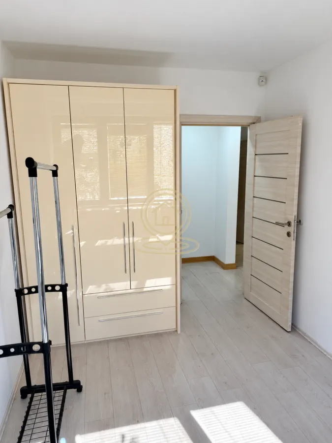 Room with a large beige wardrobe and an open clothing rack.