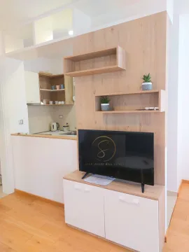 Living room with wooden wall paneling, shelves, and a television. - image 13