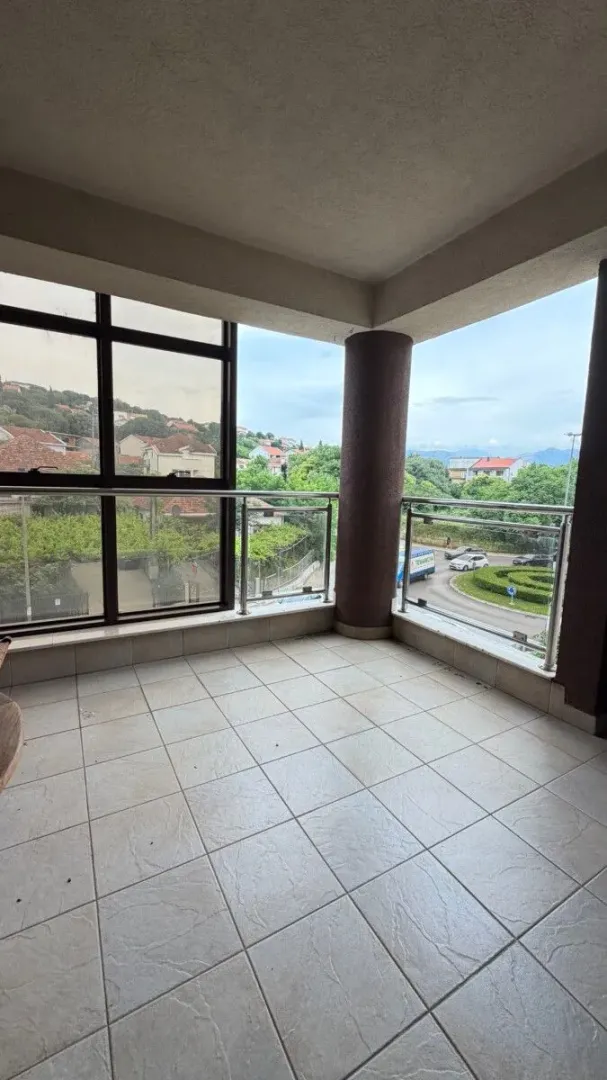 Covered terrace with tiled flooring and a glass railing.