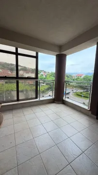 Covered terrace with tiled flooring and a glass railing. - image 11