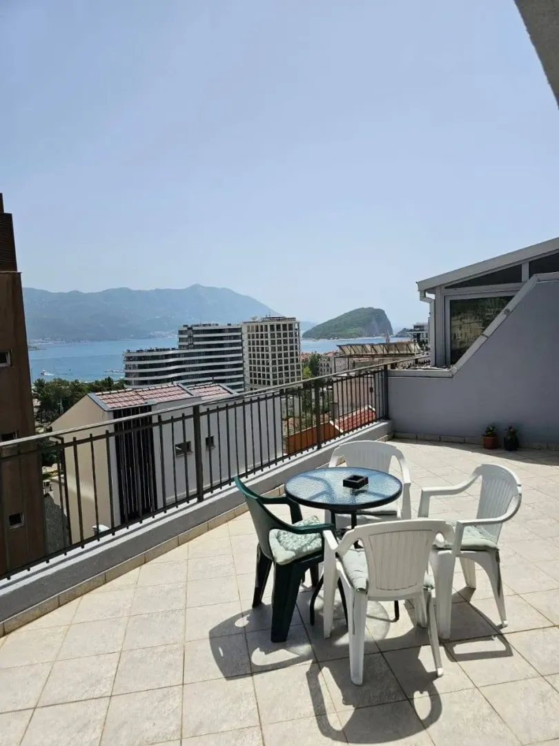 Spacious terrace with seating furniture and a view of the sea and city.