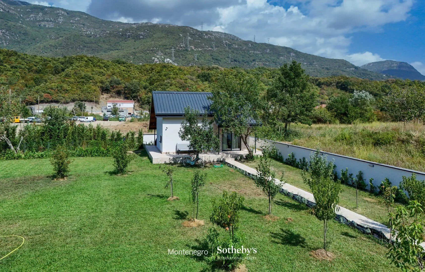 Pogled iz vazduha na kuću sa uređenim dvorištem i okolnim zelenilom.