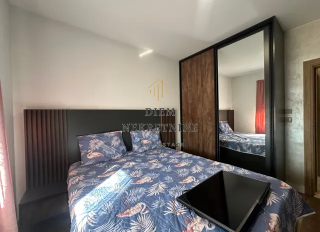 Furnished bedroom with a double bed and a large mirrored wardrobe.