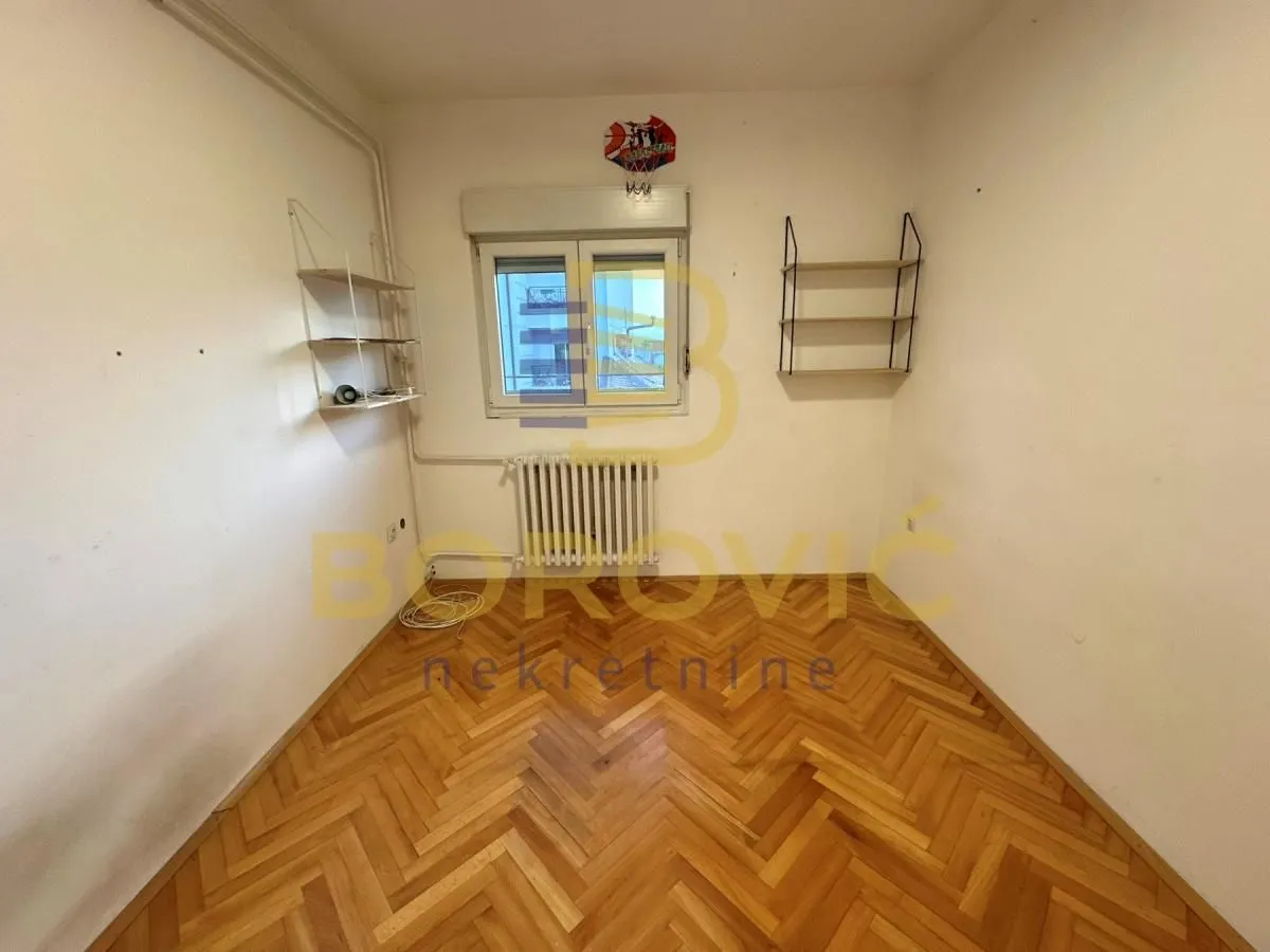 Prazna soba sa parketom i prozorom.