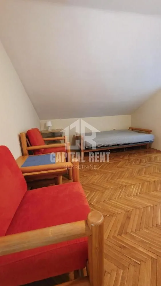 Potkrovlje sa krevetom i drvenim foteljama.