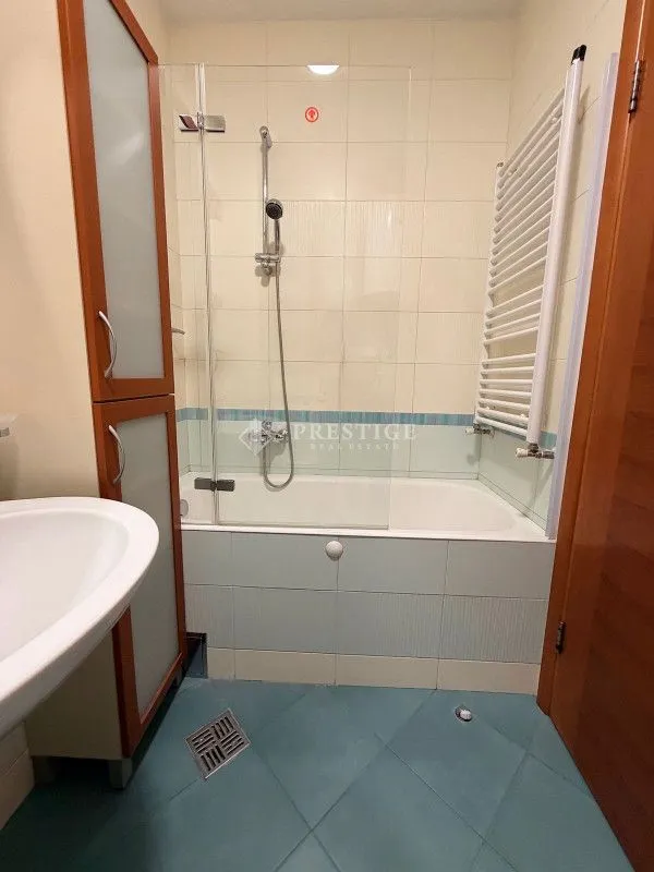 Bathroom with a bathtub, glass shower screen, and built-in cabinet.