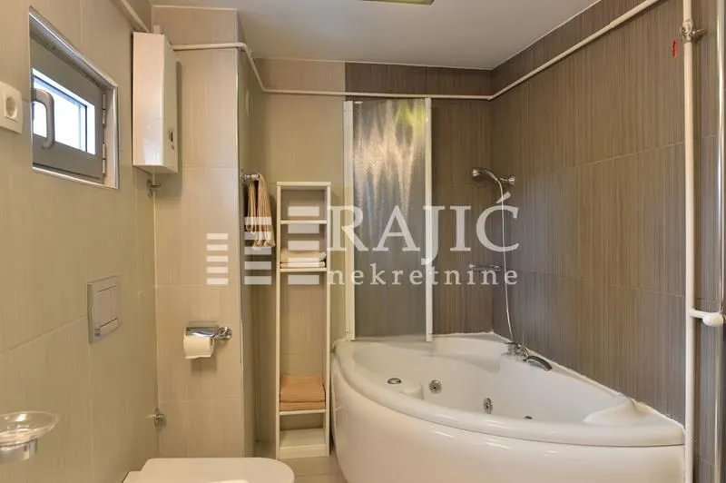 Bathroom equipped with a bathtub, sanitary ware, and shelving.