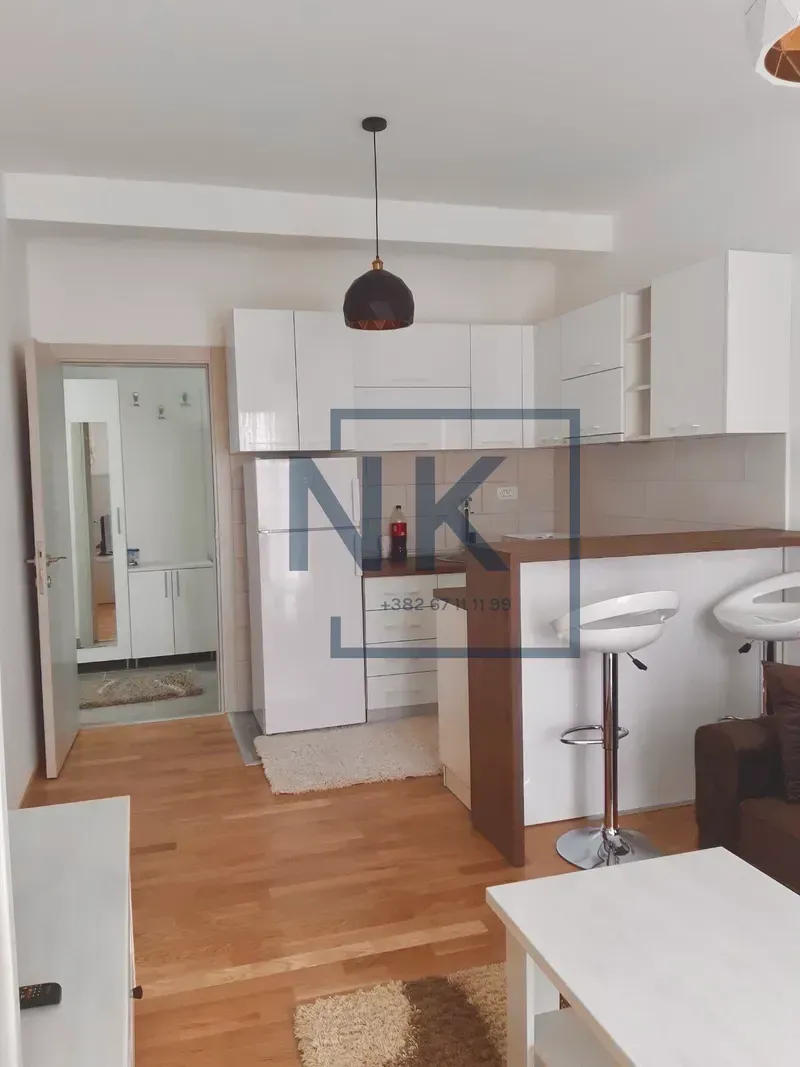 Small kitchen with white cabinets and a breakfast bar connected to the living room.