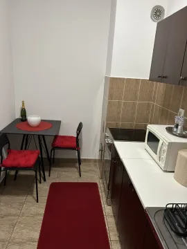 Mala kuhinja sa trpezarijskim stolom i crvenim detaljima. - image 7