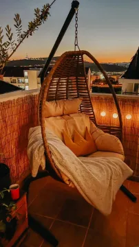 Namješten balkon sa visećom foteljom i pogledom na grad u sumrak. - image 16