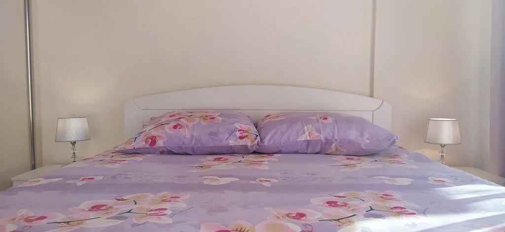 Svijetla spavaća soba sa bračnim krevetom i noćnim lampama.