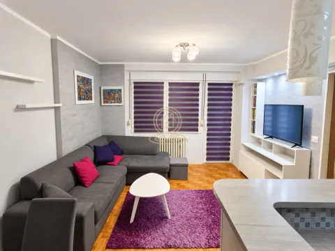 Dnevna soba sa ugaonom garniturom, TV komodom i ljubičastim detaljima. - image 2