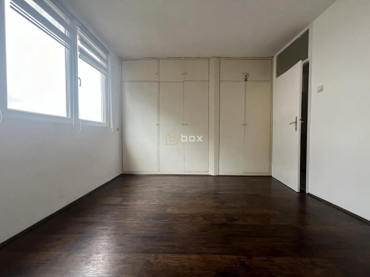 Empty bedroom with built-in wardrobes and dark wooden flooring.