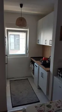 Mala kuhinja sa bijelim elementima i prozorom. - image 4