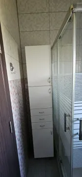 Manje kupatilo sa tuš kabinom i bijelim ormarićem. - image 8