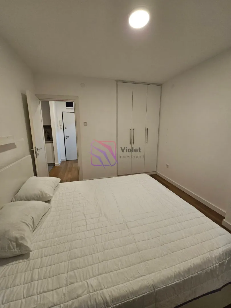 Bedroom with a double bed, white wardrobe, and a view of the hallway.