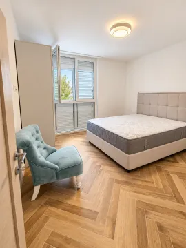 Spavaća soba sa bračnim krevetom, plavom foteljom i parketom u riblju kost. - image 10