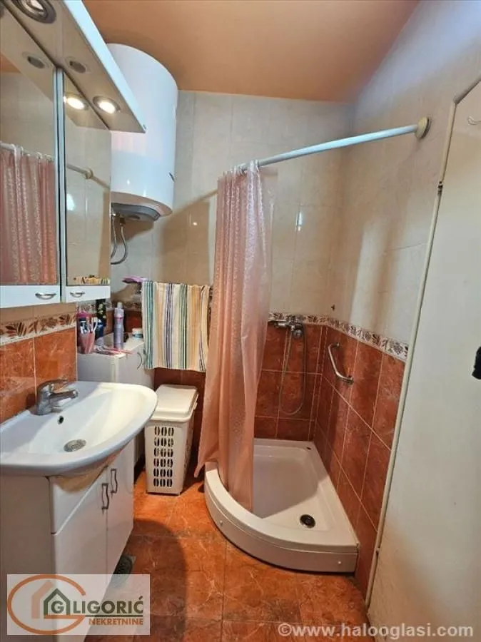 Bathroom with a shower cabin, washbasin, and water heater.