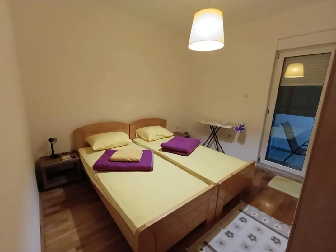 Jednostavna spavaća soba sa dva singl kreveta i izlazom na balkon.