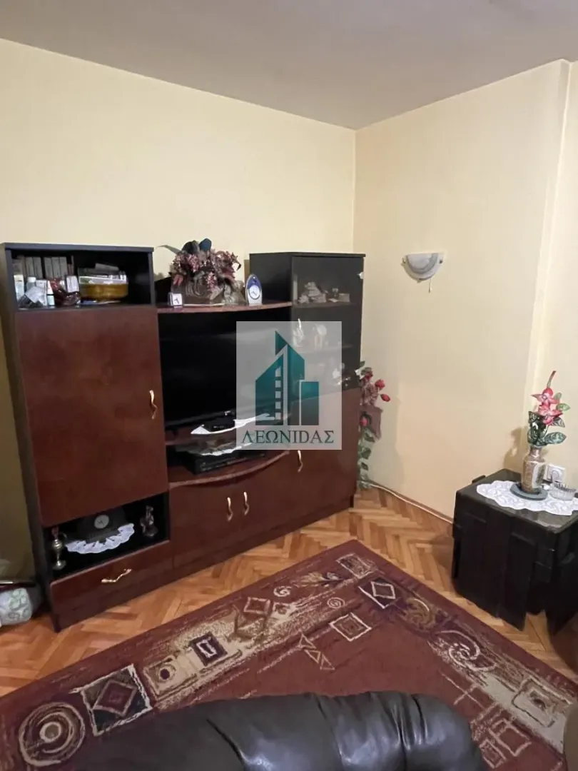 Living room with wooden furniture, a television, and a rug on the floor.