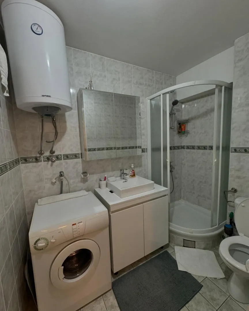Manje kupatilo sa tuš kabinom, umivaonikom, veš mašinom i bojlerom.
