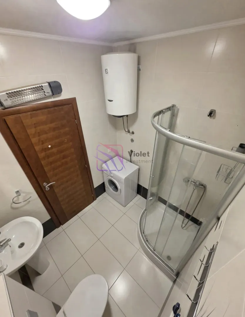 Bathroom equipped with a shower cabin, washbasin, toilet, water heater, and washing machine.