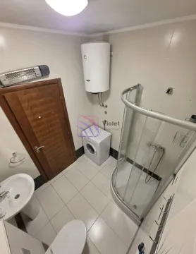 Bathroom equipped with a shower cabin, washbasin, toilet, water heater, and washing machine. - image 5